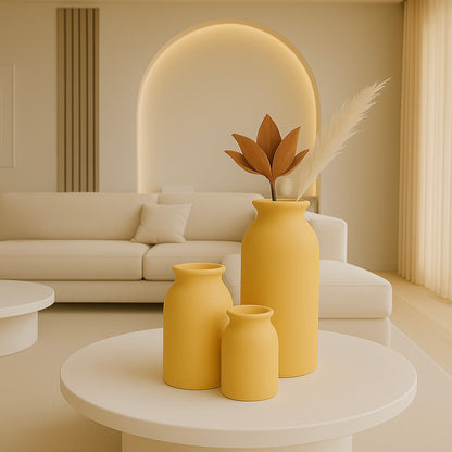 Set of three minimalist ceramic vases in soft Yellow tones, displayed on a round coffee table in a modern neutral-toned living room.